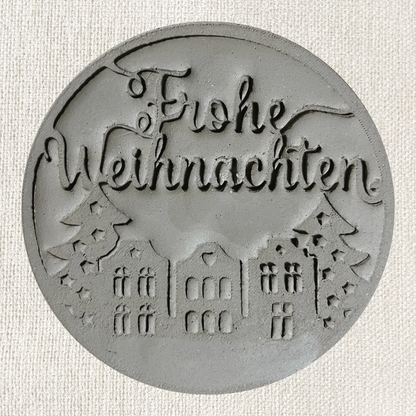 Runder Frohe Weihnachten Stempel aus Ton für Töpferwaren, mit weihnachtlichem Design und klarer Schrift.